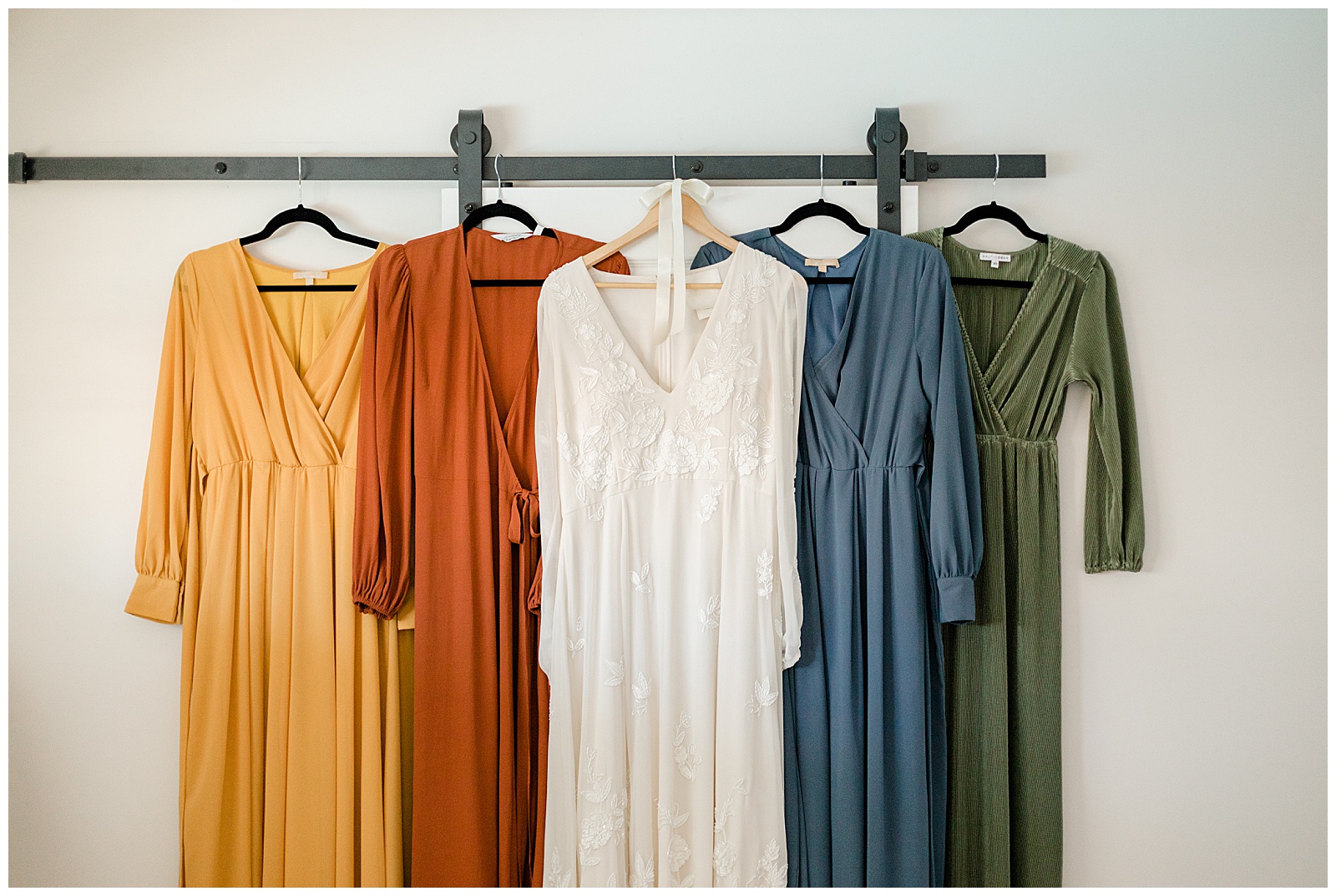 Boho colored dresses hanging on a wall.
