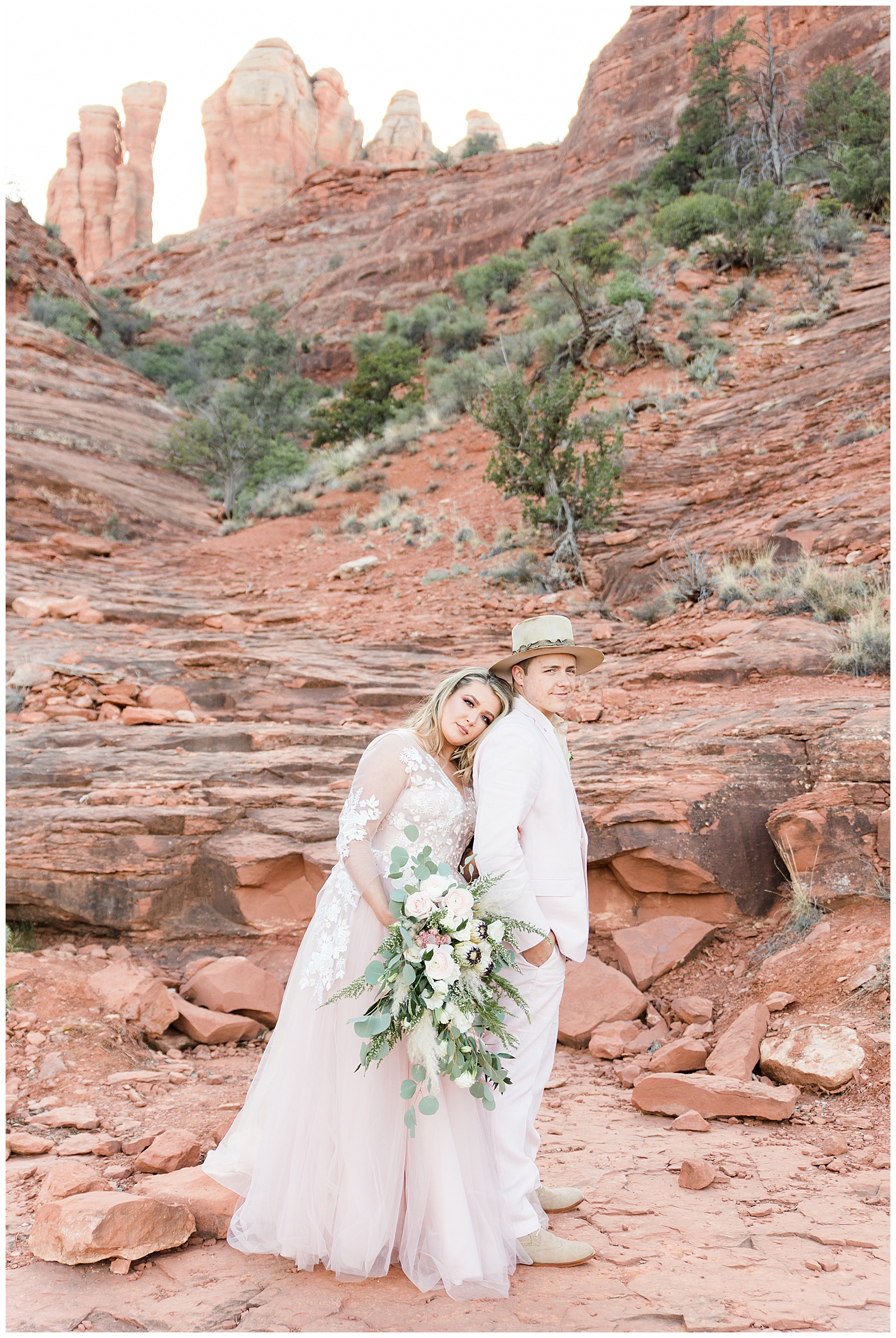 Bride leaning on groom's back in front of red rock formations