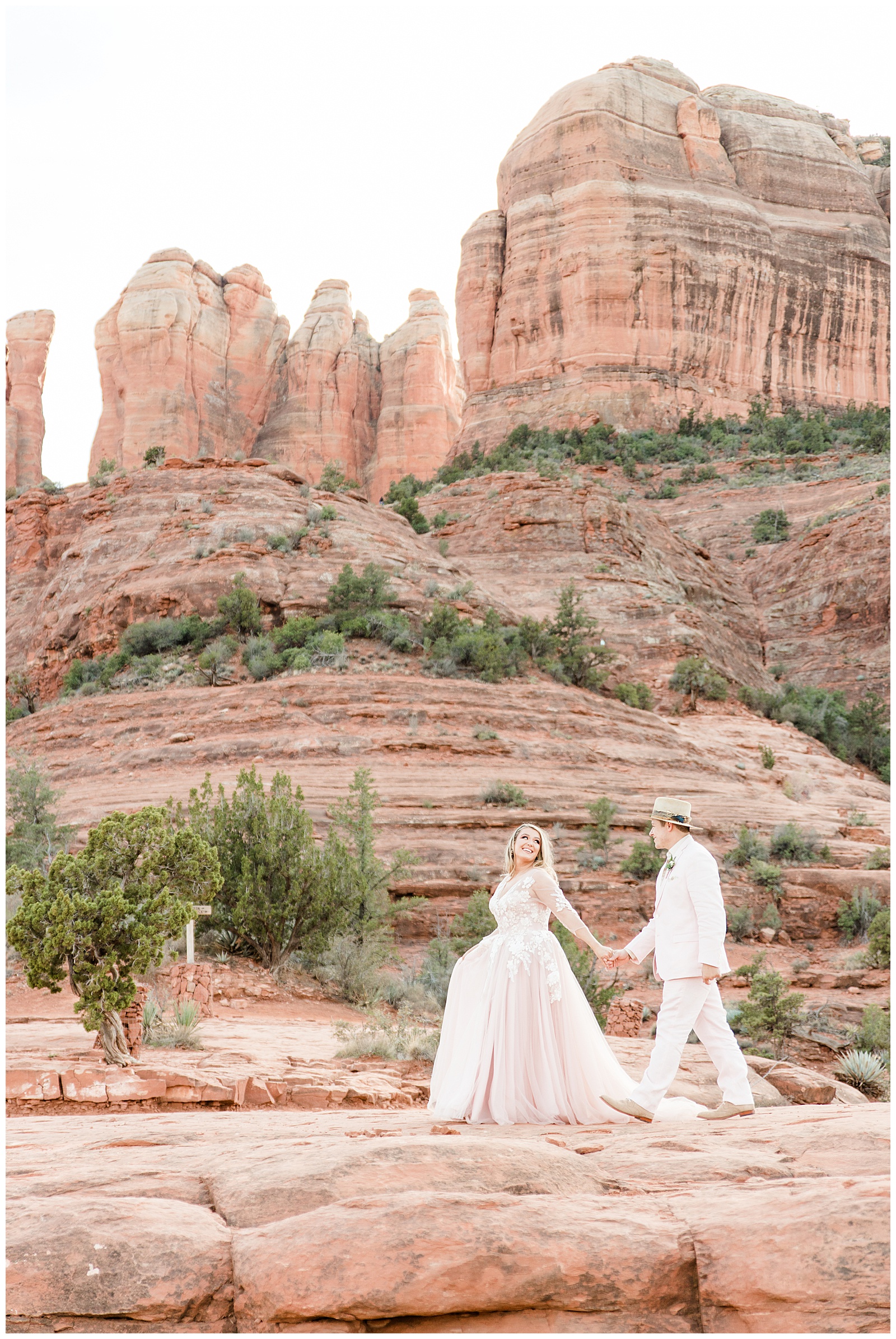 Bride looks back at groom with sprawling view of Cathedral Rock