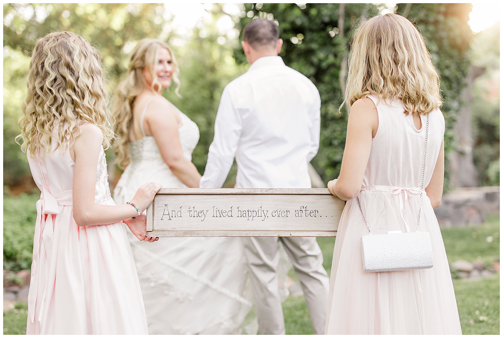 Young girls hold a sign saying And they lived happily ever after... at their intimate wedding